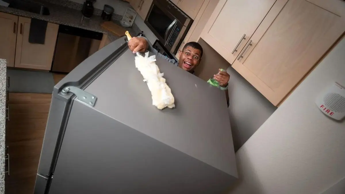 a-man-cleaning-the-top-of-refrigerator