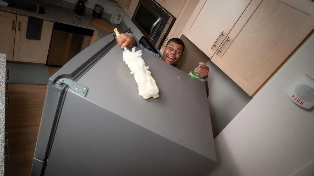 a-man-cleaning-the-top-of-refrigerator