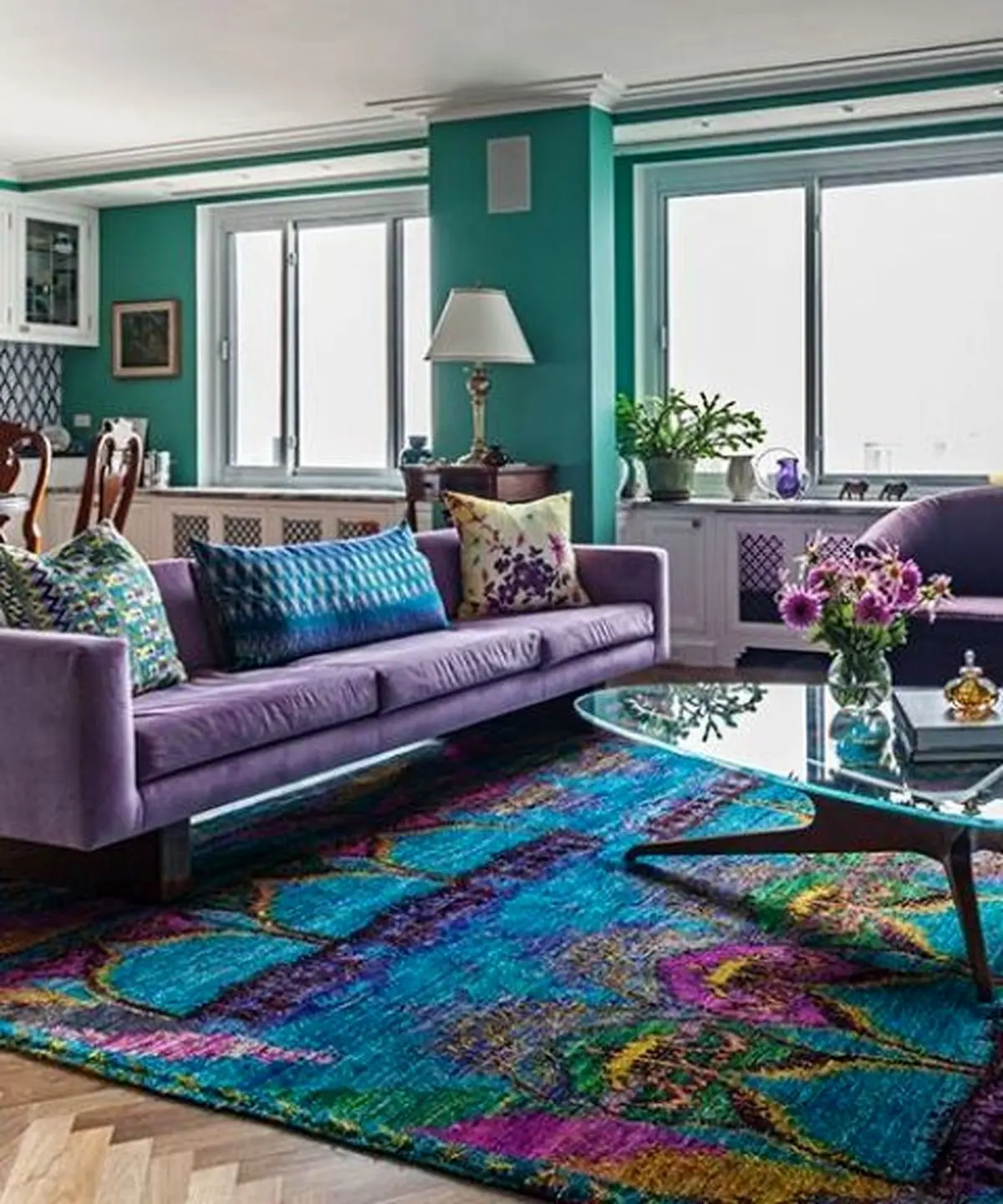 02-a-bright-living-room-with-green-walls-a-purple-sofa-and-chairs-a-bright-rug-with-purple-touches-and-a-glass-coffee-table