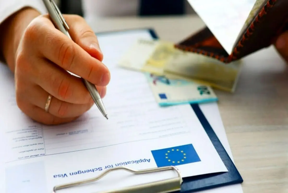 تکمیل فرم درخواست ویزای شینگن همراه با پاسپورت و مدارک هویتی روی میز