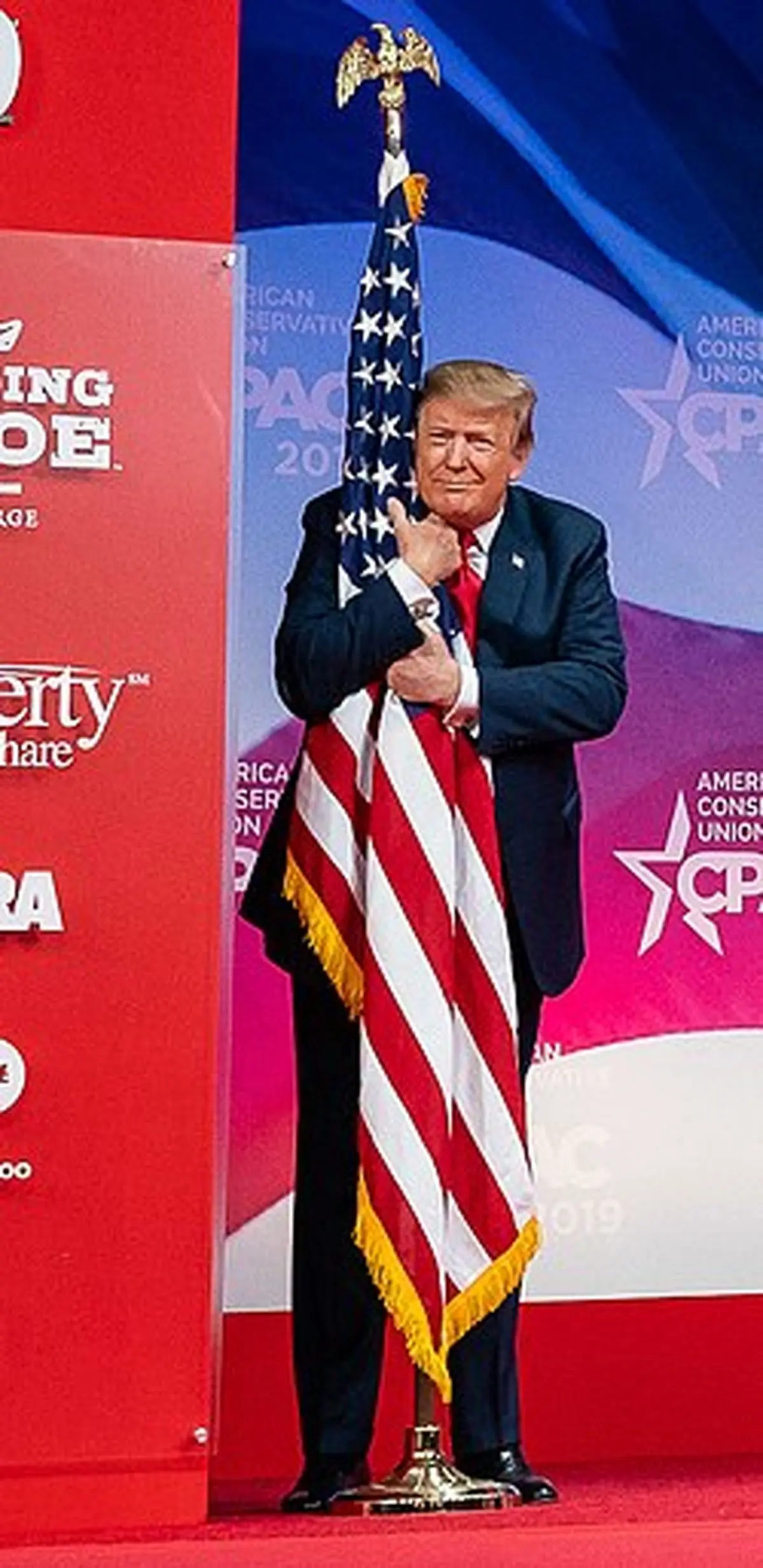 President_Donald_J._Trump_embraces_the_American_flag_at_CPAC_2019
