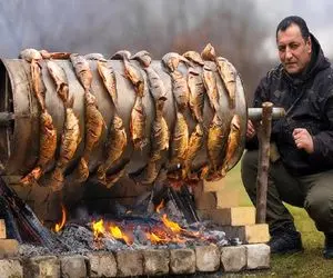 غذای باحال؛ ماهی دودی هارو زنجیره ای به هم وصل کرد پیچید دور بشکه رو آتیش کبابی شه